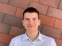 a man smiling in front of a brick wall